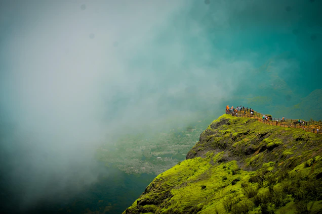 A group of smiling backpackers standing on a lush green hilltop with fog rolling in behind them, capturing the spirit of Meghalaya’s rainforest adventure.