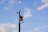 A utility pole with attached transformer and wires set against a clear blue sky with scattered clouds.