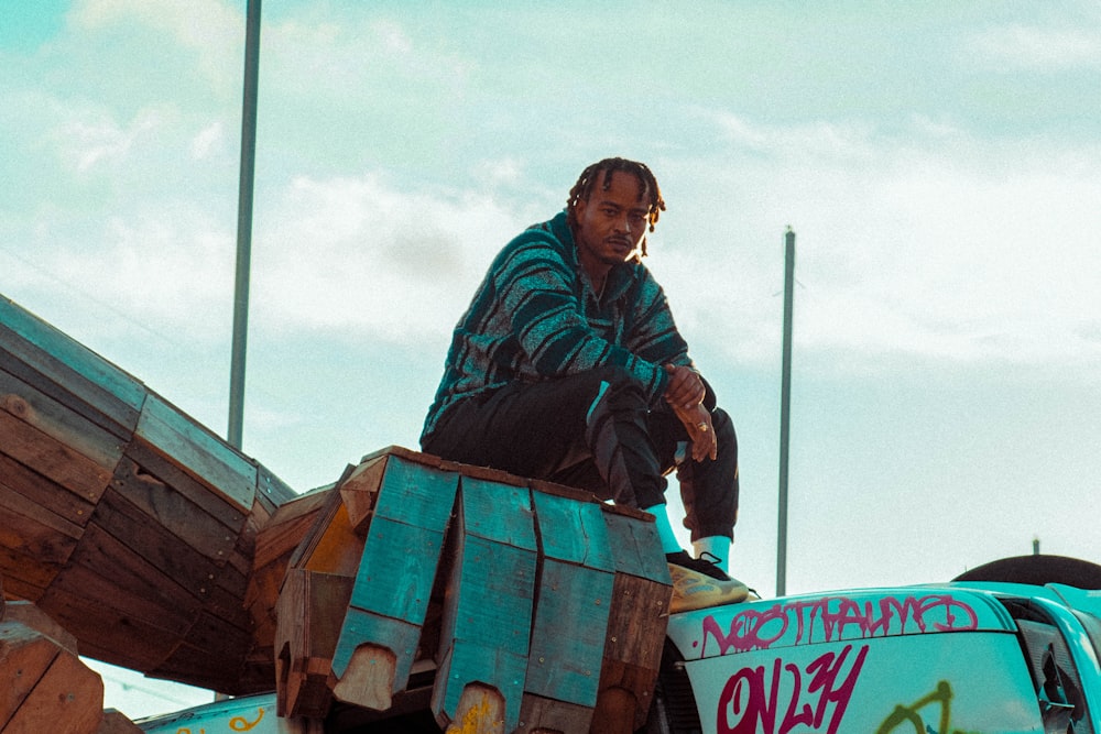 man in green jacket sitting on brown wooden cart