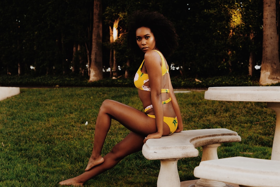 woman in yellow bikini sitting on white concrete bench