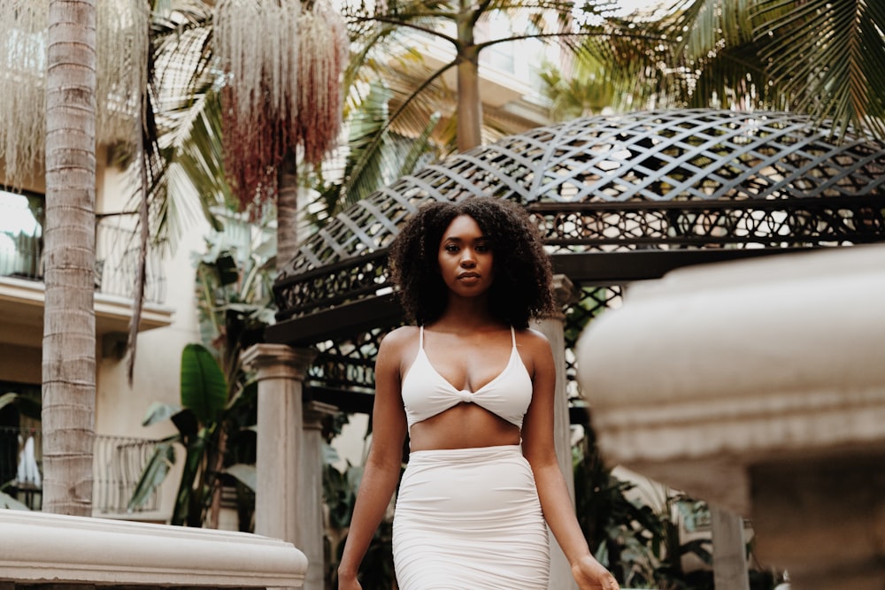 woman in white halter top dress standing near black metal gate