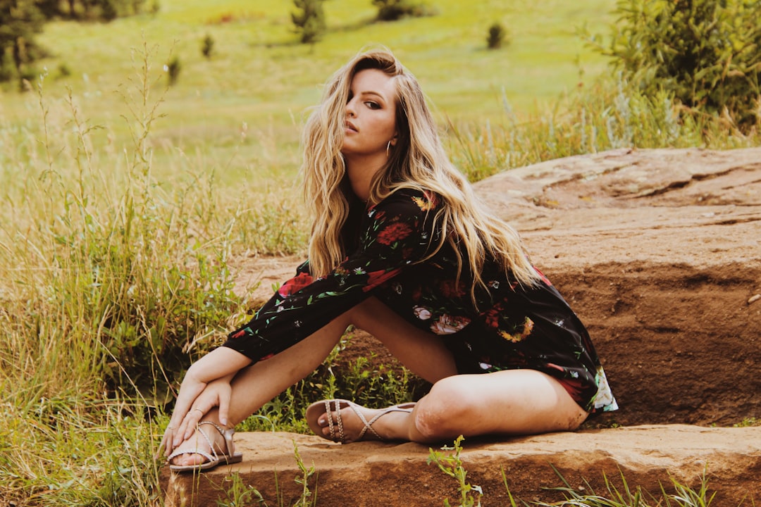 woman in black and red dress sitting on brown grass field during daytime