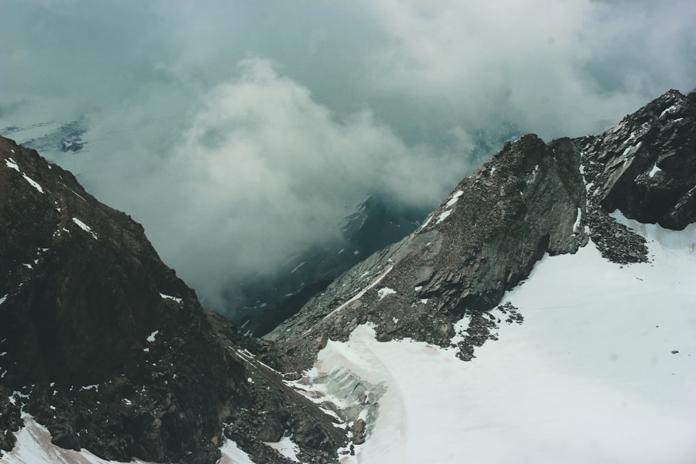 brown rocky mountain covered with snow under white clouds