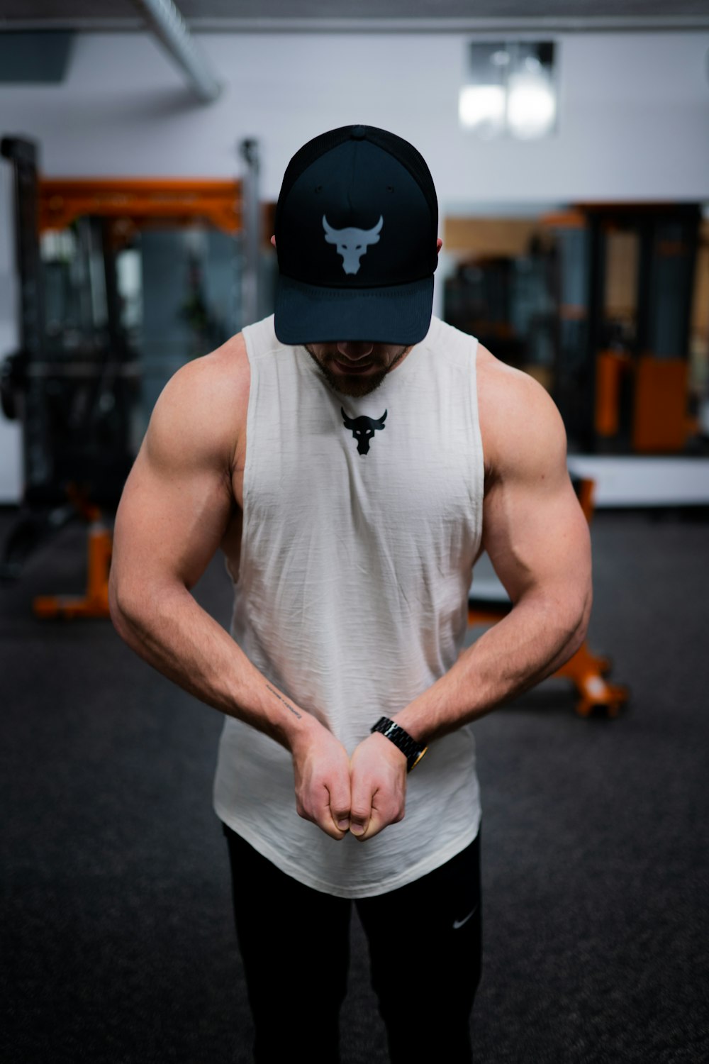 man in white tank top wearing black cap