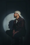 man in black and red plaid dress shirt wearing white cap