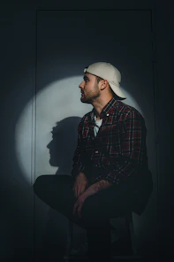 man in black and red plaid dress shirt wearing white cap
