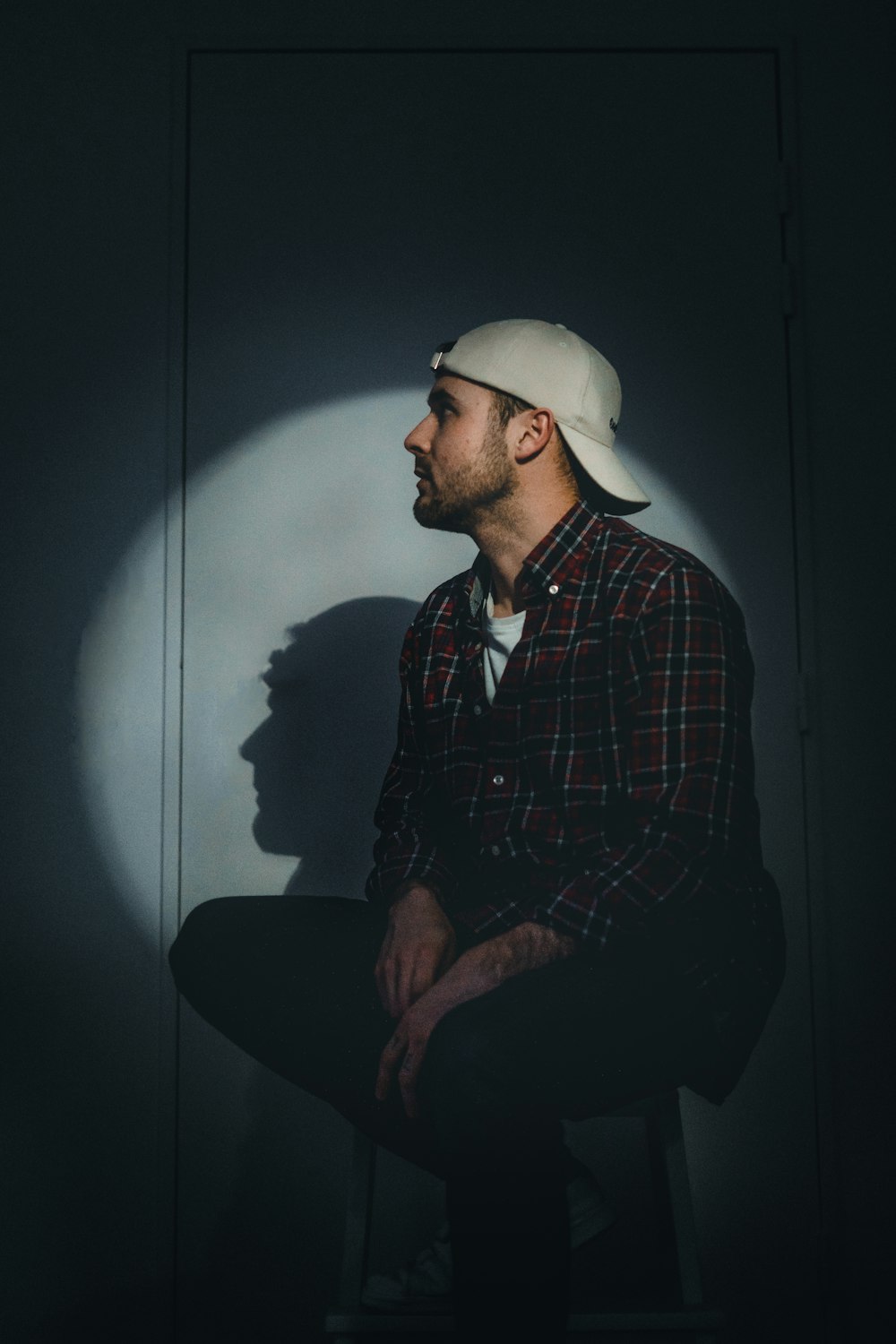 man in black and red plaid dress shirt wearing white cap