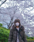 woman in black jacket standing near trees during daytime
