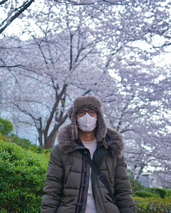 woman in black jacket standing near trees during daytime