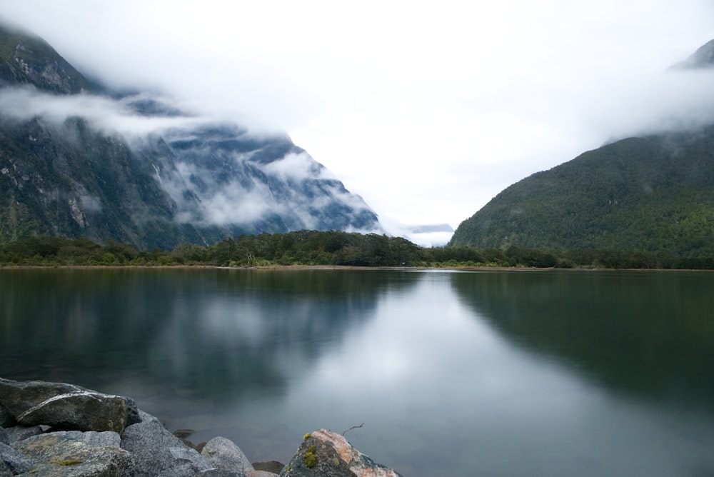 lake near green trees and mountain during daytime