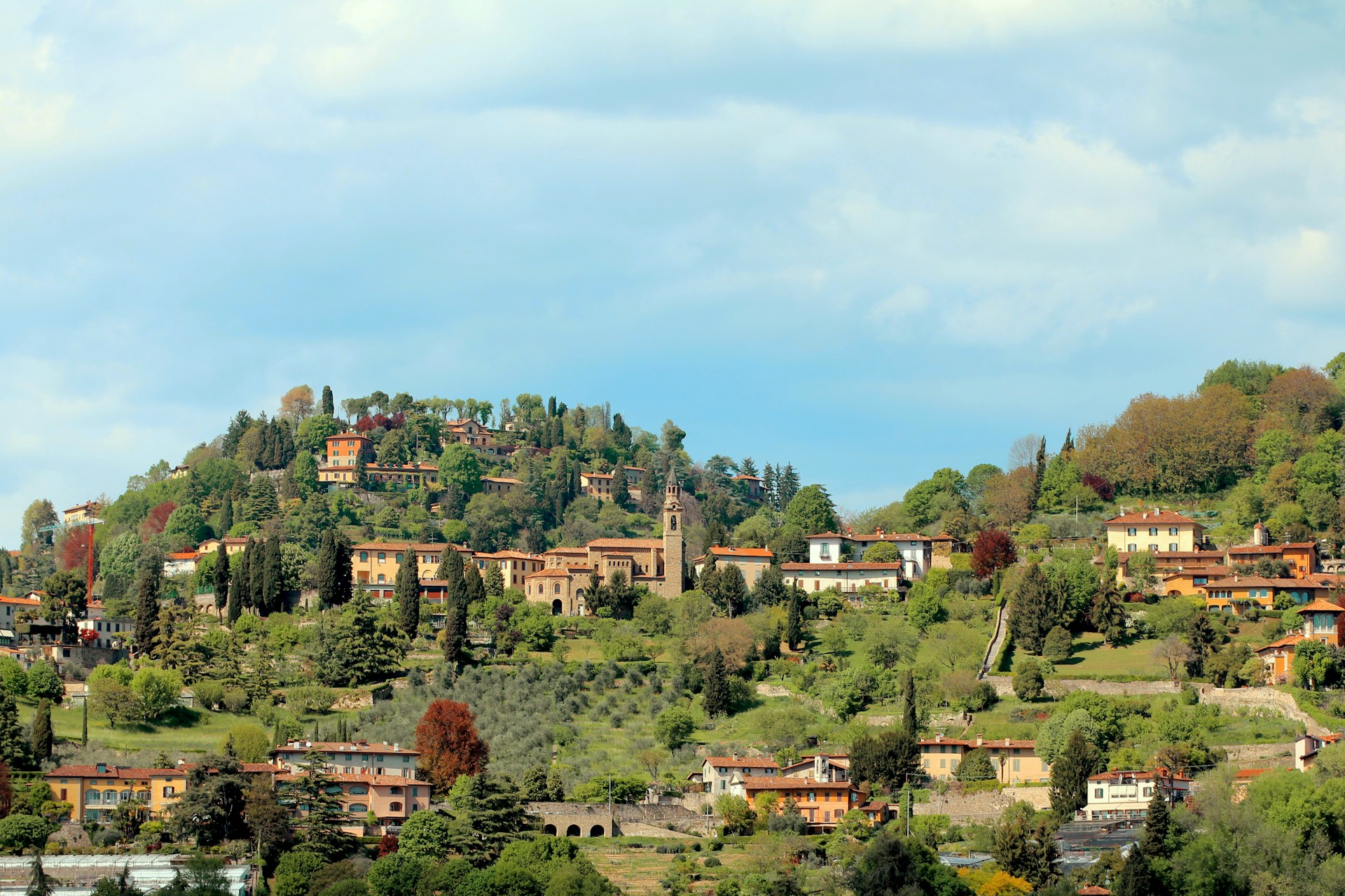 A panoramic view of a quiet hillside with three villas surrounded by lush greenery.