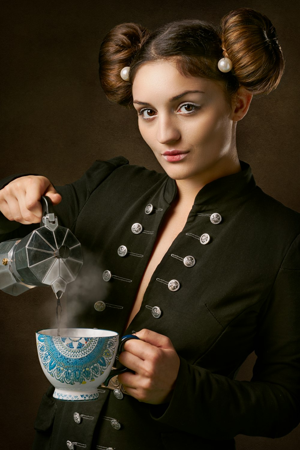 woman in black coat holding blue and white ceramic mug