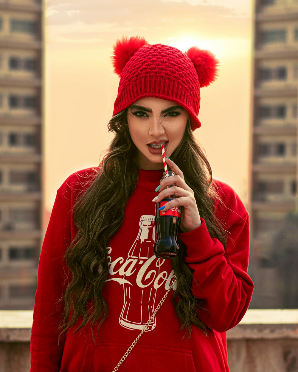 Mujer con sudadera roja con capucha bebiendo Coca Cola