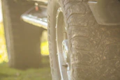 Close-up of rugged 4x4 tires gripping rocky terrain with dust rising in the background.