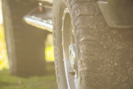 Close-up of rugged 4x4 tires gripping rocky terrain with dust rising in the background.