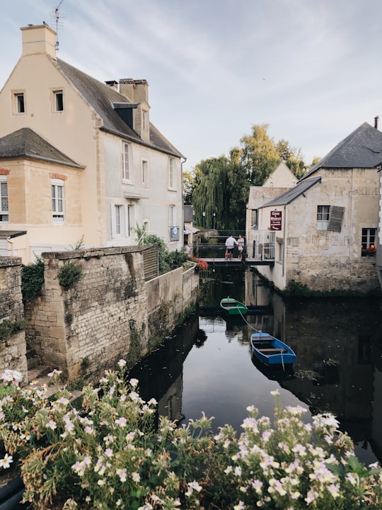 white and brown concrete building beside river during daytime in Bayeux France