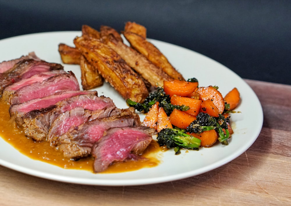 carne cotta con verdura verde su piatto in ceramica bianca