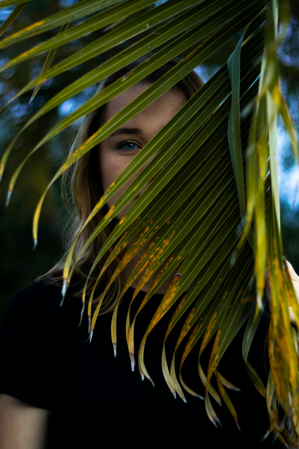 Femme en chemise noire debout à côté d’une plante verte