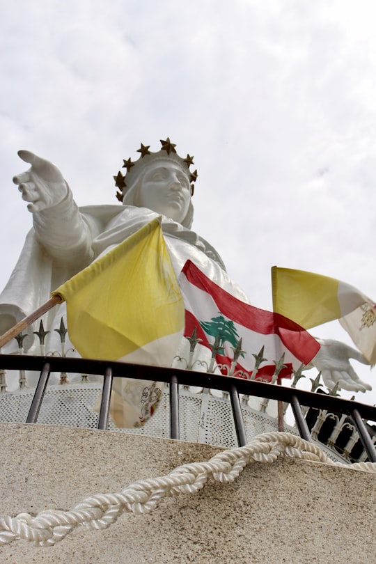 white concrete statue of man holding flag of america in Harissa Lebanon