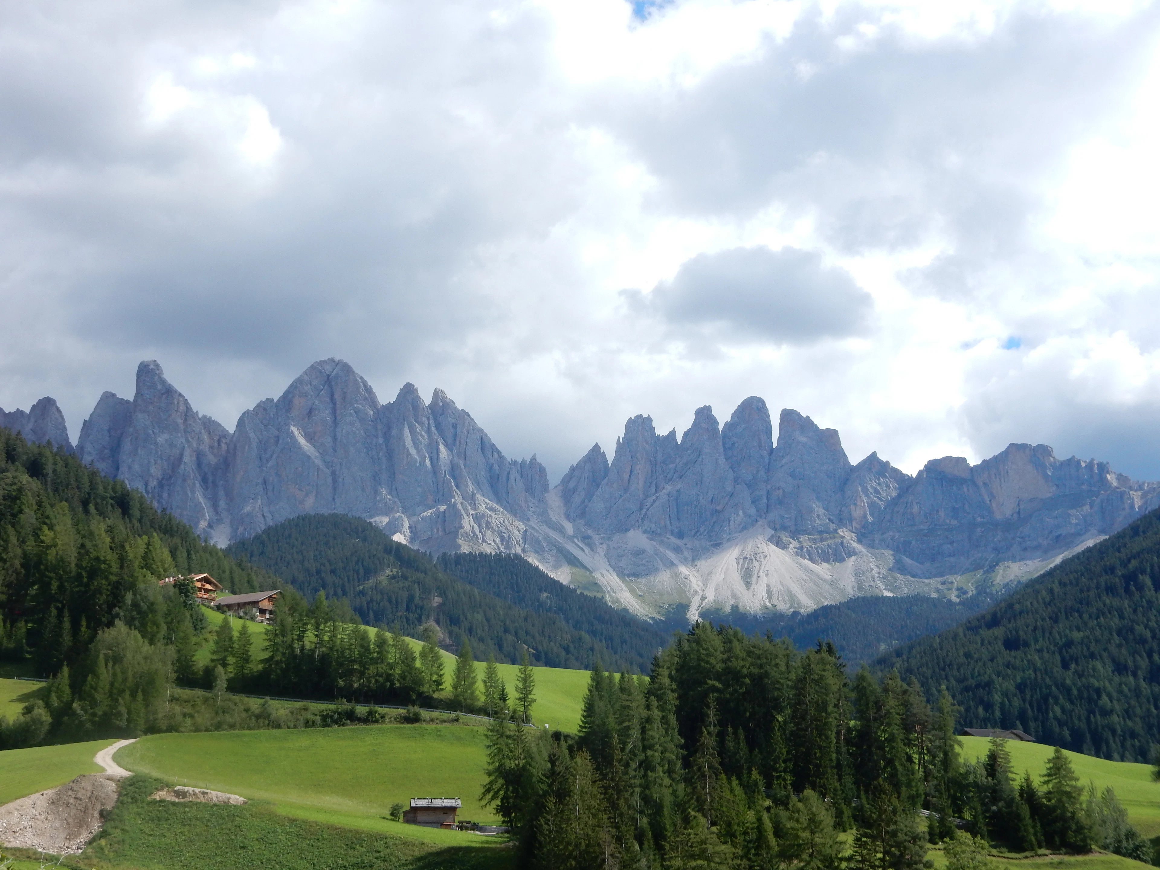 Green meadows and forest in Val di Funes beneath the Odle peaks