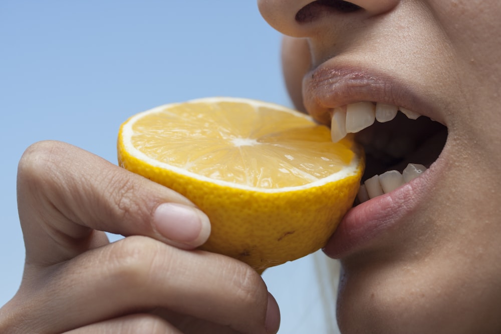 personne tenant des fruits oranges pendant la journée