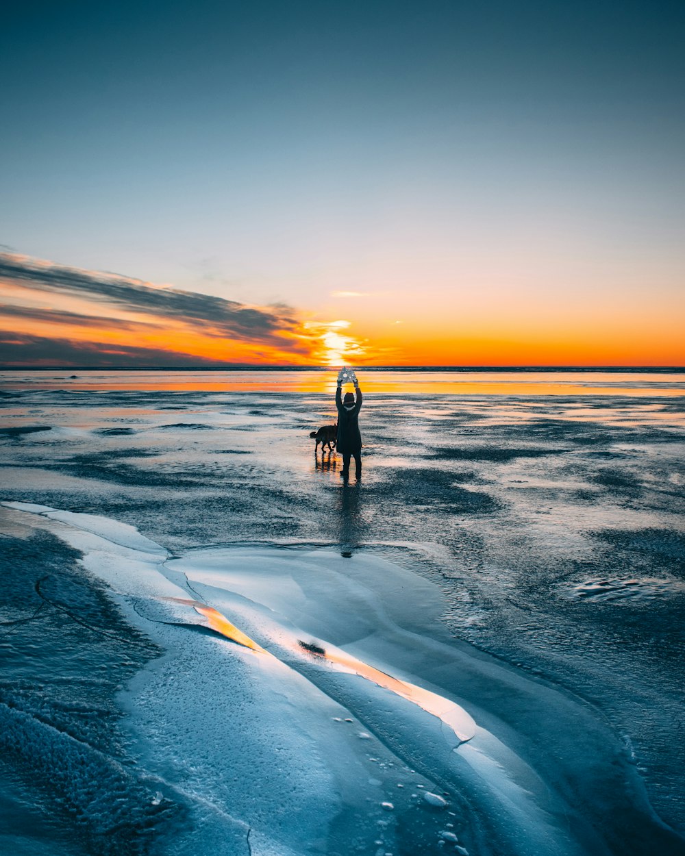 Hombre en chaqueta negra de pie en la orilla del mar durante la puesta del sol