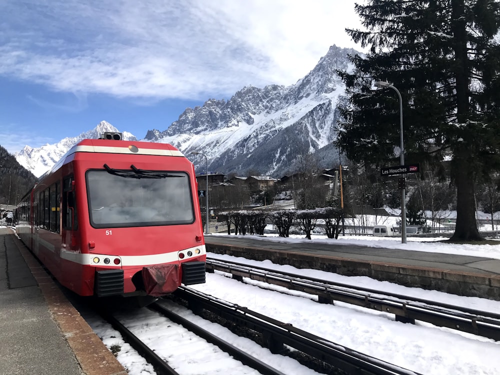 red train on rail road near snow covered mountain