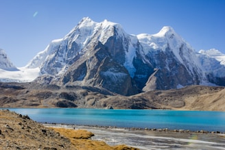 snow covered mountain near body of water during daytime