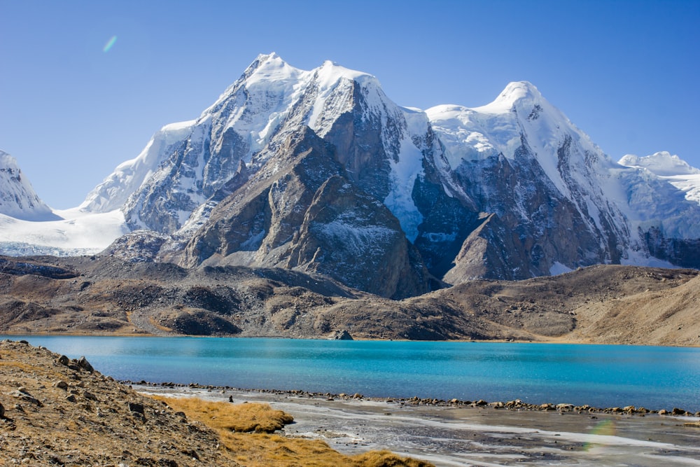 snow covered mountain near body of water during daytime