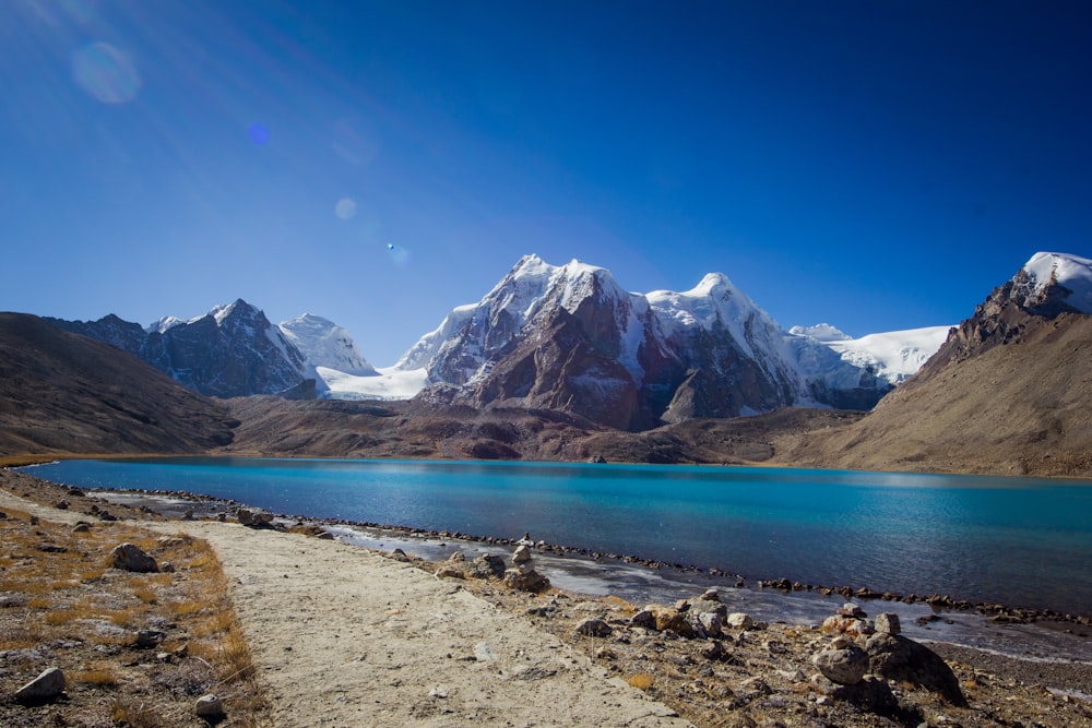 Lago cerca de la montaña cubierta de nieve bajo el cielo azul durante el día