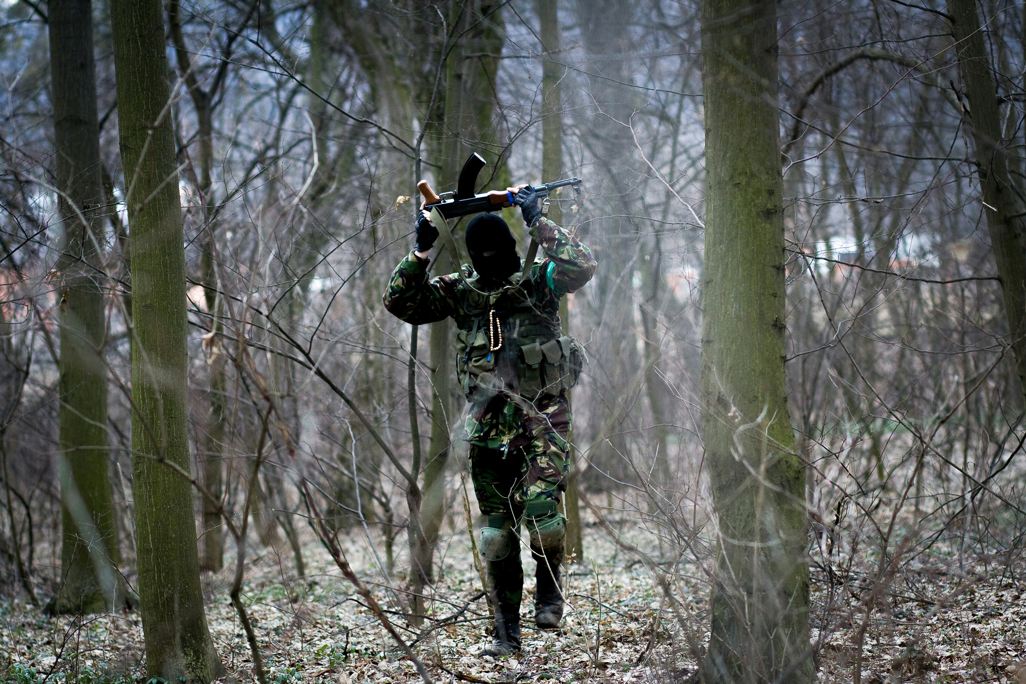 man in green and brown camouflage uniform carrying black and white backpack
