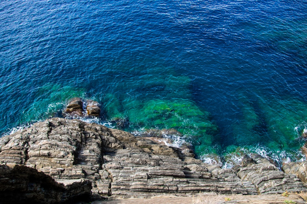 brown rocky mountain beside blue sea during daytime