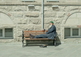 homme en veste noire assis sur un banc en bois marron