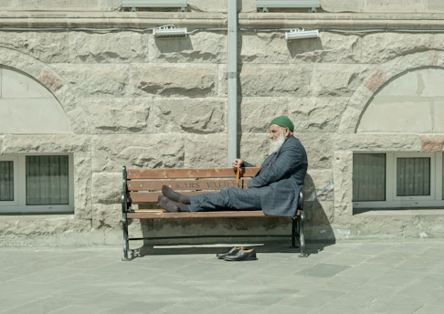 homme en veste noire assis sur un banc en bois marron