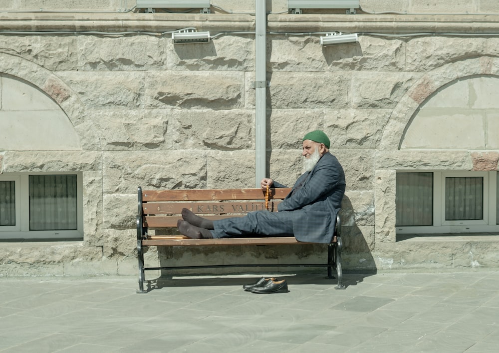 man in black jacket sitting on brown wooden bench