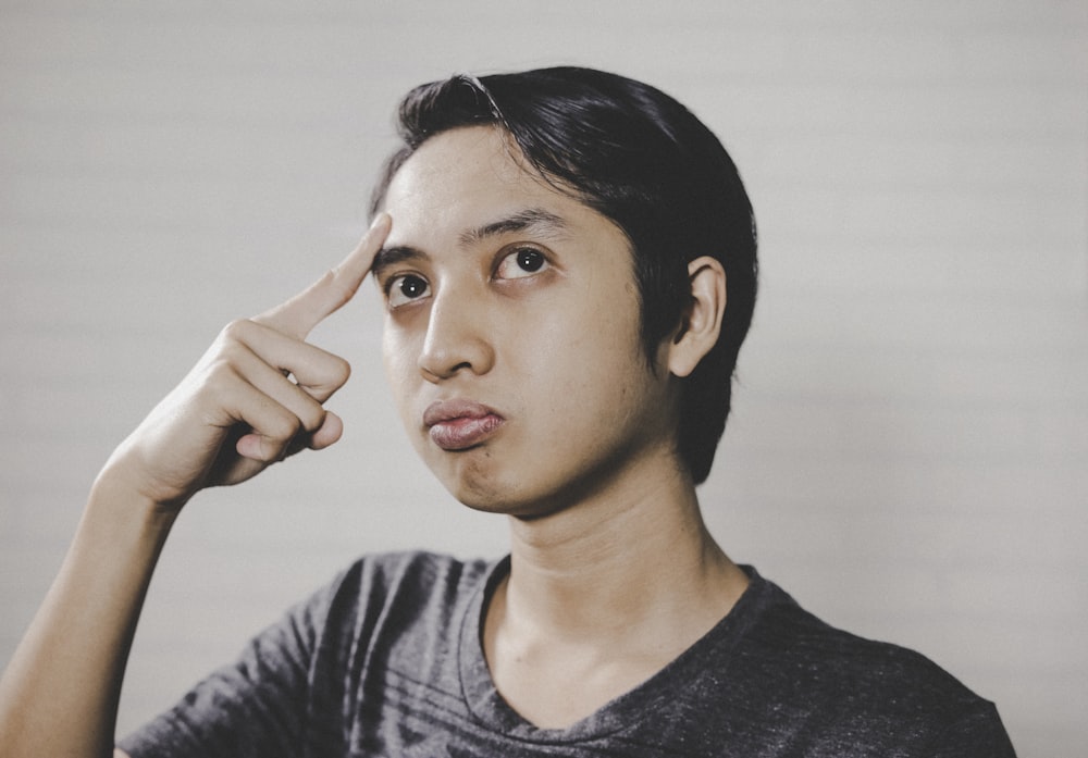 Person pointing to their head indicating thinking