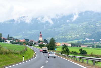 cars on road near green grass field during daytime