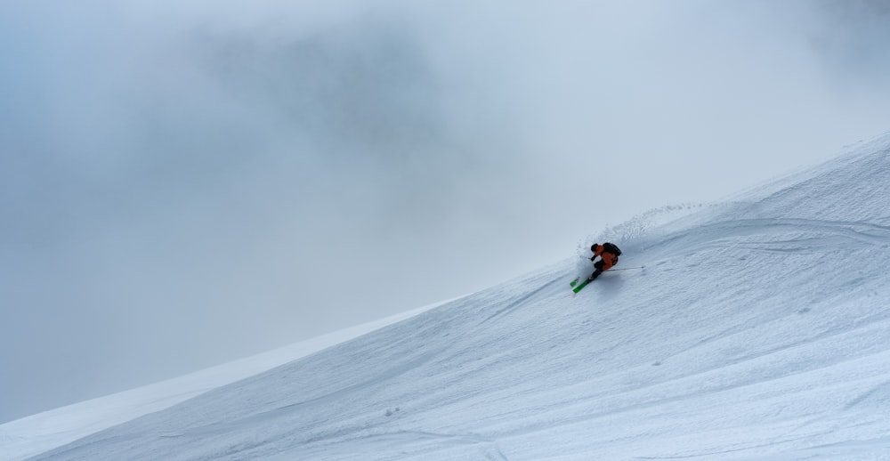 person in red jacket riding on snow board during daytime