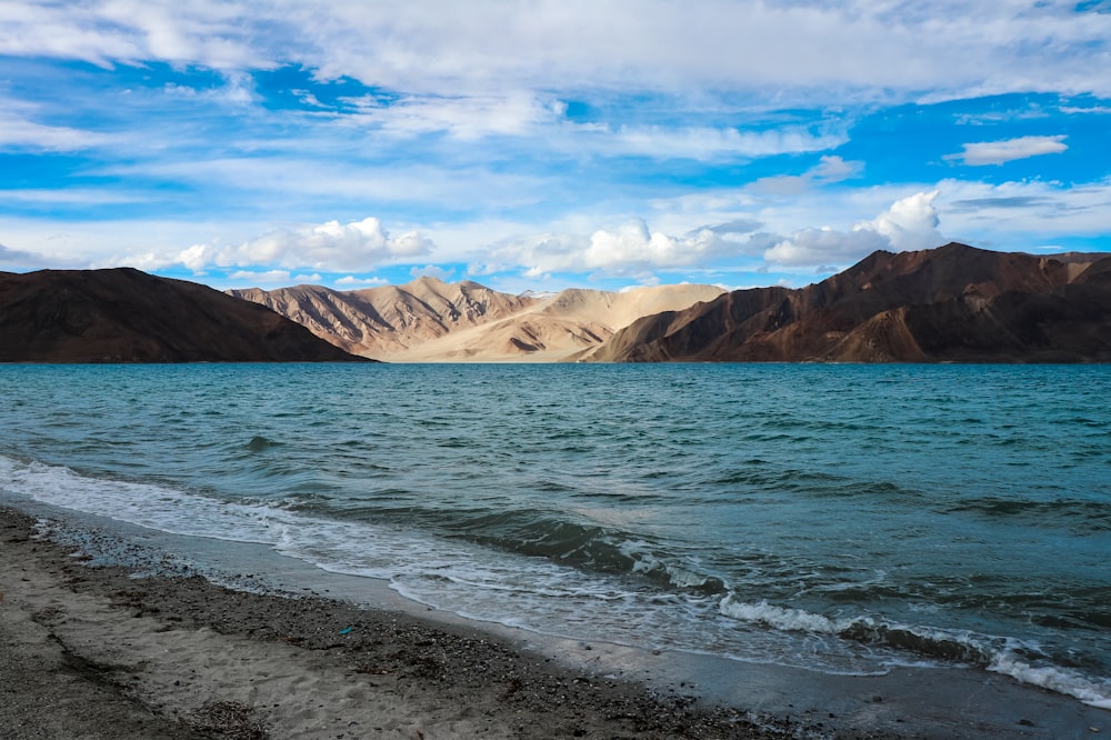 body of water near mountain under blue sky during daytime