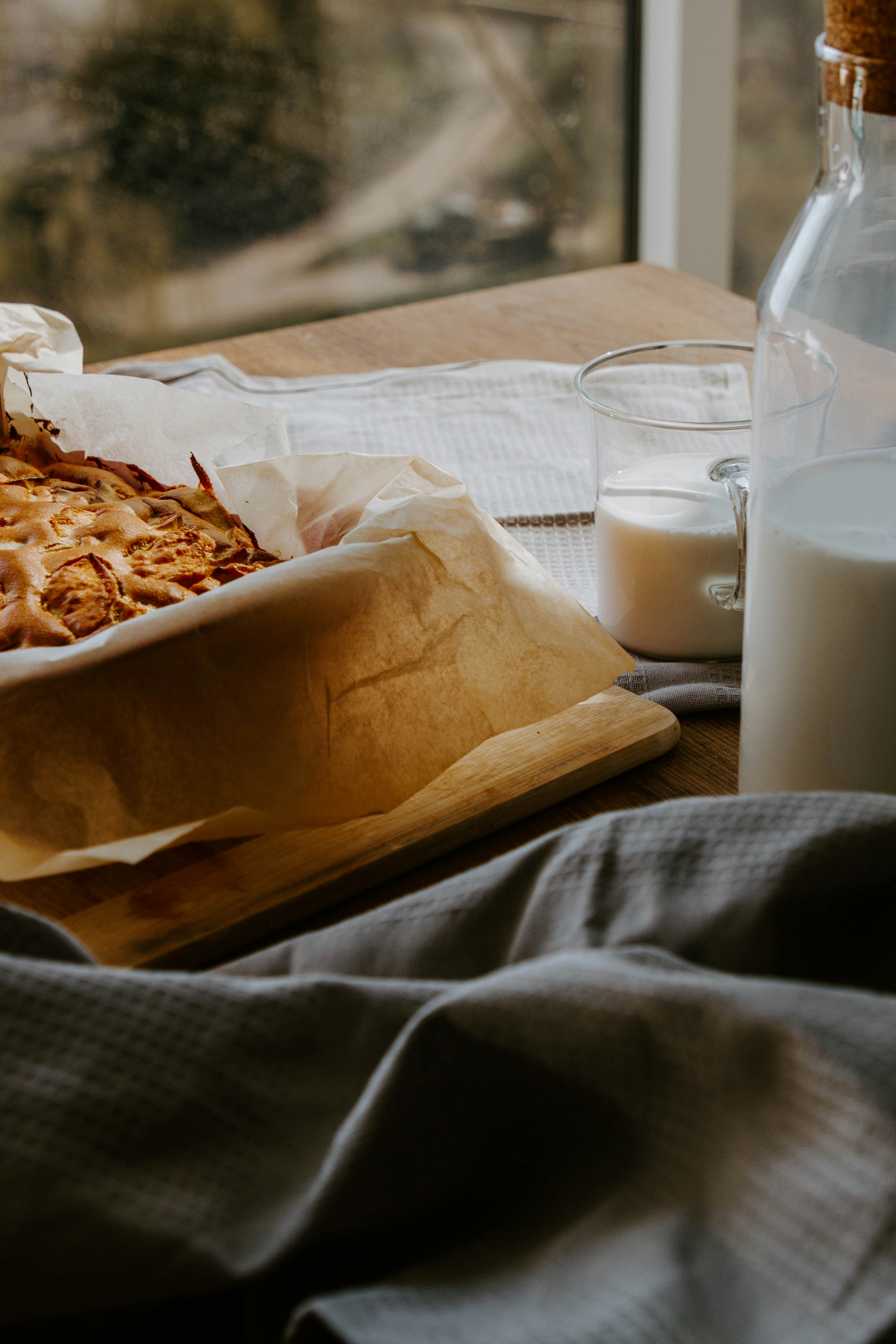 bread on brown paper bag beside clear drinking glass with milk