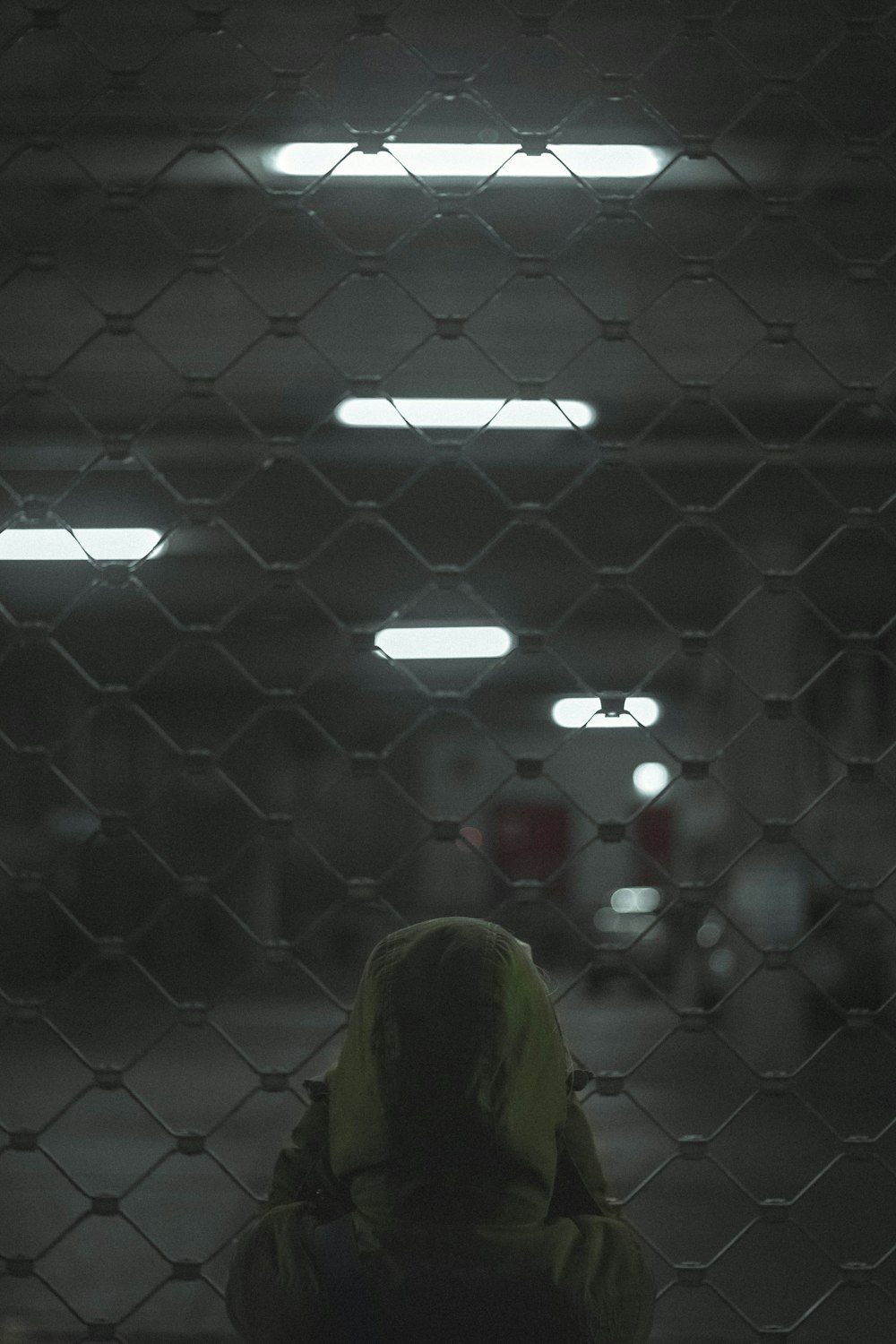 person in yellow shirt standing near gray metal fence