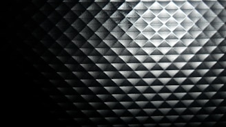 Close-up of a dark graphite textured surface with subtle geometric blockchain patterns illuminated by soft navy blue highlights.