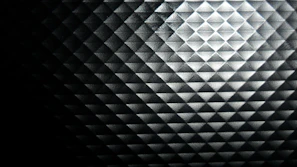 Close-up of a diamond-shaped light reflection on a dark, textured surface.