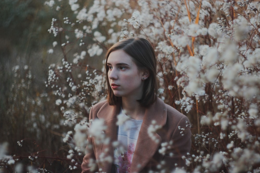 woman in white long sleeve shirt standing near white flowers during daytime