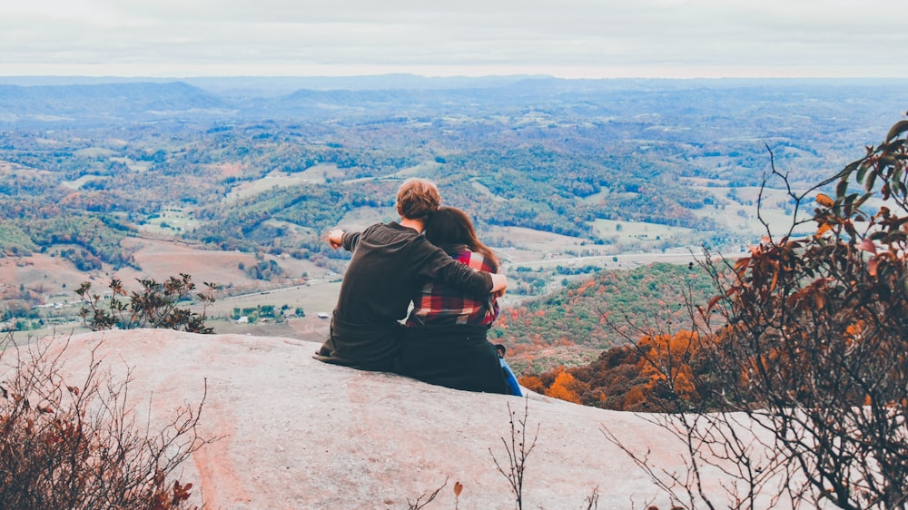 woman in black jacket sitting on rock during daytime