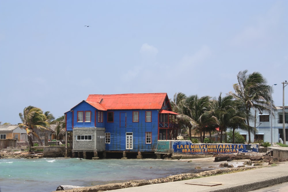 blue and red house near body of water during daytime