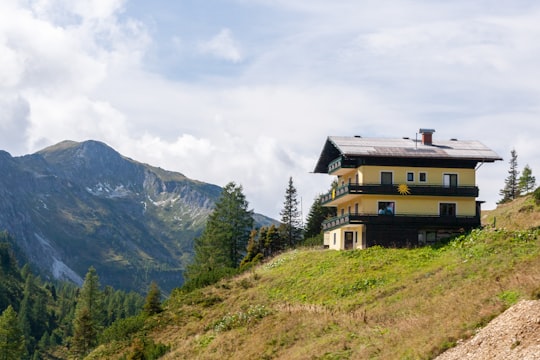 brown wooden house on green grass field near mountain under white clouds during daytime in Land Salzburg Austria