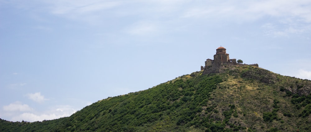 brown concrete building on top of green mountain