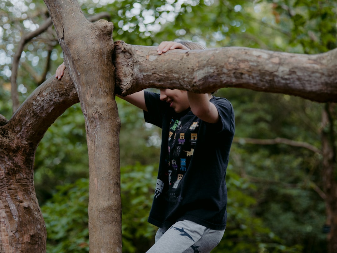 man in black t-shirt and gray pants sitting on brown tree branch during daytime