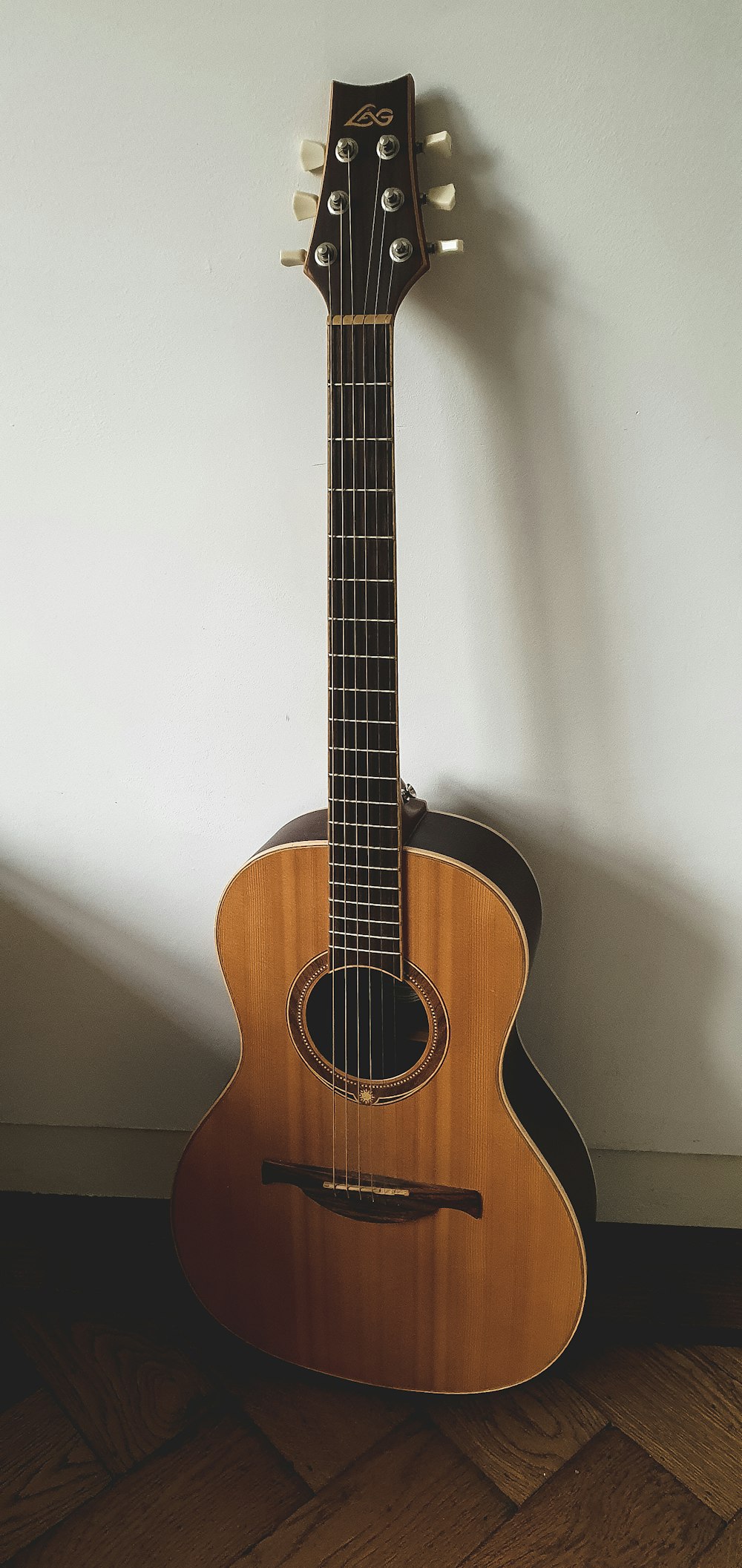 brown acoustic guitar on white wall